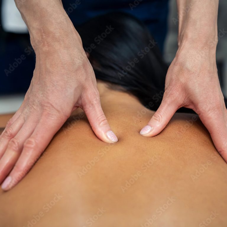 Attractive girl is relaxing on classic massage procedure in spa. Manual therapy. Masseur is doing back massage